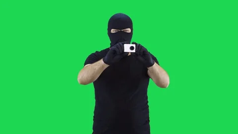 A man in a balaclava takes off an action camera while holding it in his hands Stock Footage 129246835