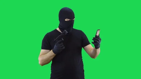 A man in a balaclava talking via video calling on a smartphone,green screen Stock Footage 129042493