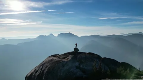 Man balancing on a rock on the Mountain top, Drone shot Stock Footage 289575245