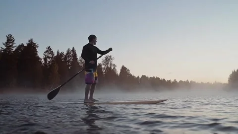 Man balancing on surf board with paddle Stock Footage 164890422