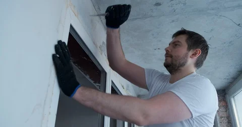 Man on balcony with knife cuts polyurethane foam, plastic door, cuts foam Stock Footage 129838474
