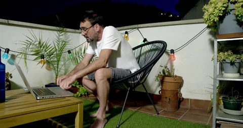 Man on Balcony with Laptop at Night: Stock Footage 336316498