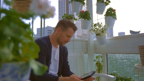 Man on balcony is looking on tablet Stock Footage 103142469