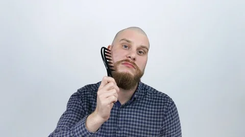 A man with a bald head combing his red beard comb and looking at the camera Stock Footage 122005476