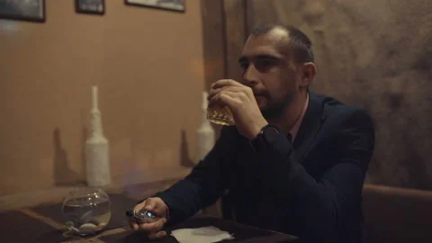 A man in a bar drinks whiskey and smokes a cigarette Video stock 95953377
