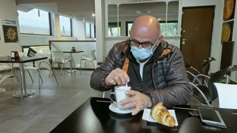 Man at Bar Having Breakfast While Wears a Medical Mask During Covid-19 Pandemic Stock Footage 141385213