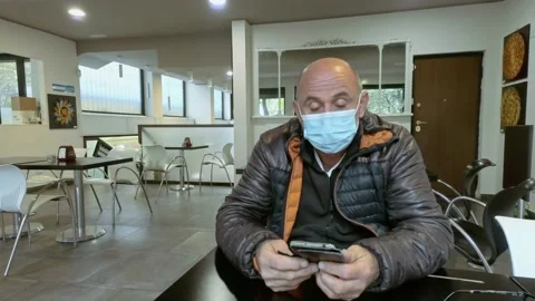 Man at Bar Using Smartphone While Wears Medical Mask During Covid-19 Pandemic Stock Footage 141385649
