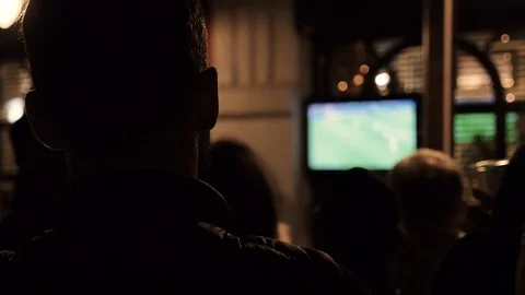 Man in a bar watching football game on a TV Stock Footage