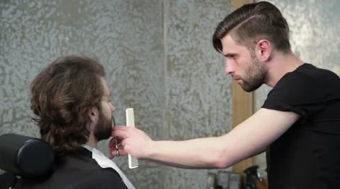Man barber cutting client's beard with scissors at hairdressing salon Stock Footage 62977621