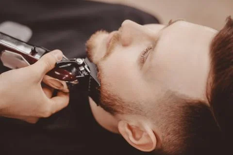 Man Barber shaves beard of client on chair Barbershop 스톡 사진