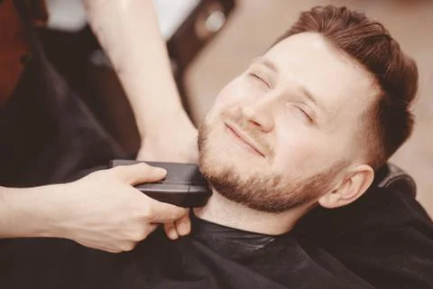 Man Barber shaves beard of client on chair Barbershop Stock Photos
