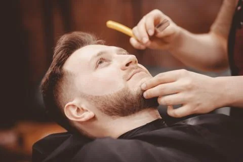 Man Barber shaves beard of client on chair Barbershop Stock Photos