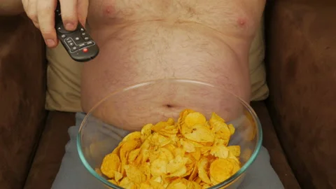 A Man With A Bare Belly Drinks Beer And Eats Chips Stock-Footage 147550050
