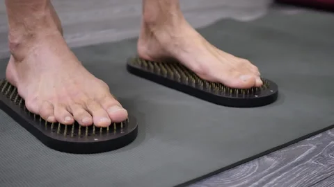 A man with bare feet steps on Sadhu's boards with sharp nails to gain energy and Stock Footage 221866306