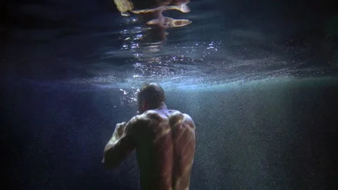 A man with a bare torso is boxing in dark water with bubbles and is reflected in Stock-Footage 195945494