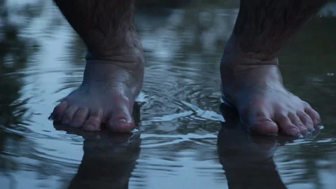 A man barefoot jumping on a puddle on the asphalt in rainy weather Stock Footage 107689921