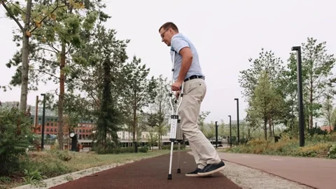 A man barely hobbles on one leg with crutches. Adult male walking slowly down Stock Footage 297578525