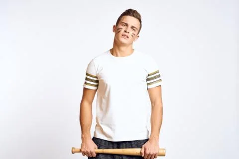 A man with a baseball bat on a light background exercises kicks sport ball model Stock Photos