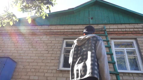 A man in a baseball cap and a plaid shirt approaches and climbs Stock Footage 210359952