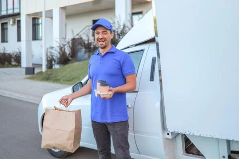 Man in baseball cap and uniform holding order from restaurant near truck fast Stock Photos