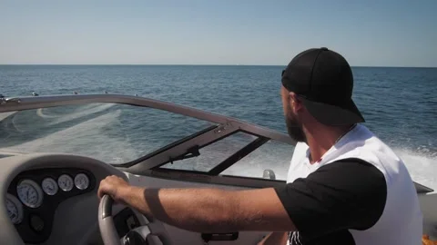 A man in a baseball cap drives a speedboat Stock Footage 160425975