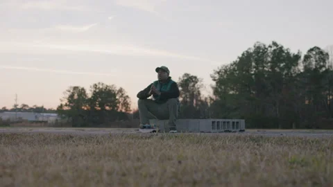 Man in Baseball Hat and Jacket Bows Head in Prayer at Sunset Stock Footage 208792608