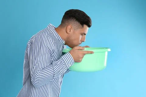 Man with basin suffering from nausea on light blue background. Food poisoning Stock Photos