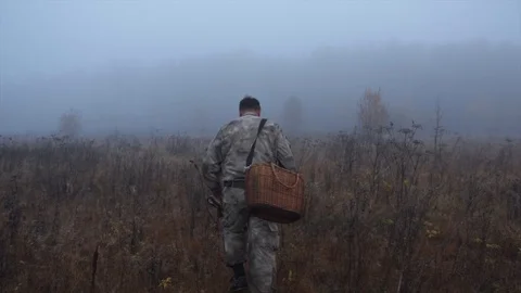 A man with a basket is walking across the field among the fog Stock Footage 124209159