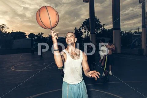 Man On Basketball Court Balancing Basketball On Finger Smiling