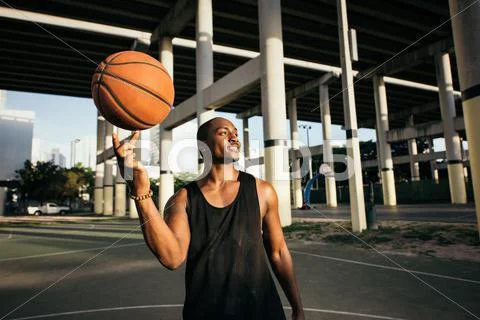 Man On Basketball Court Balancing Basketball On Finger Looking Away