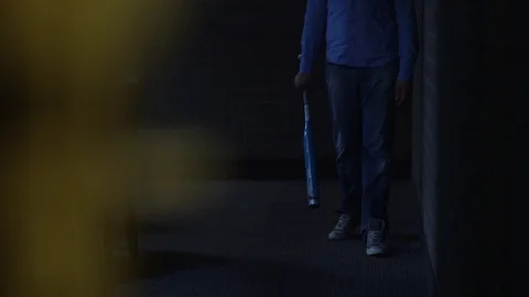 Man With Bat Walks Towards Camera In A Dark Room Stock Footage 126700435