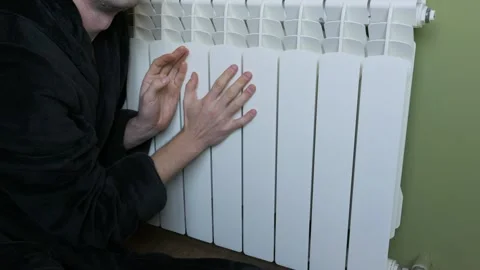Man In Bathrobe Checking Temperature Of Heating Radiator In Cold House Stock Footage 329134692
