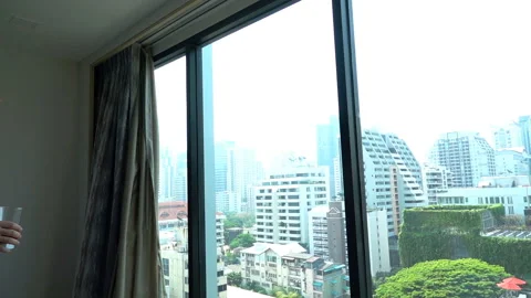 Man in bathrobe drinking juice and admires the view from the window, slow motion Stock Footage 88158715