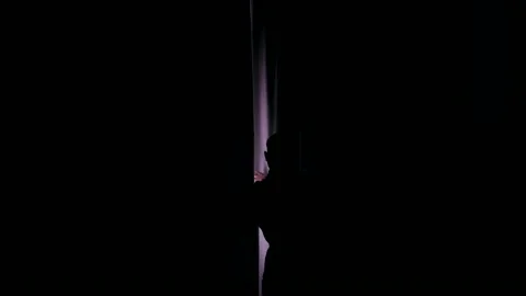 A man in a bathrobe opens the curtains view from the back Stock Footage 233885048