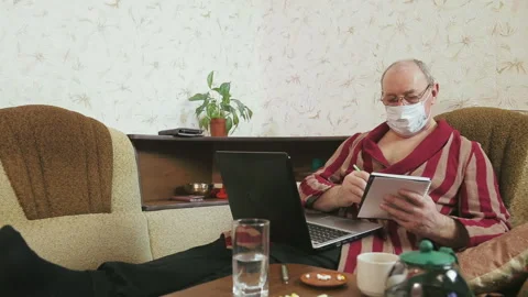 A man in a bathrobe in quarantine self-isolation is doing remote work on the Stock Footage 129064083