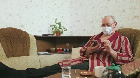 A man in a bathrobe in quarantine self-isolation communicates in a smartphone on Stock Footage 130283010