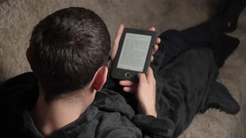 Man in a Bathrobe Reads an E-book While Sitting on the Couch Vídeo Stock 171232666