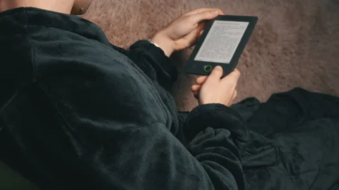 Man in a Bathrobe Reads an E-book While Sitting on the Couch Stock Footage 171233233