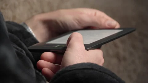 Man in a Bathrobe Reads an E-book While Sitting on the Couch Stock Footage 171234259