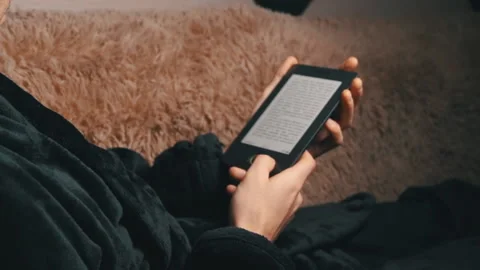 Man in a Bathrobe Reads an E-book While Sitting on the Couch Stock Footage 171472743