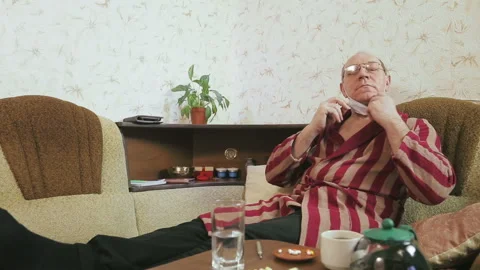 A man in a bathrobe on the sofa at home with flu-like symptoms is drinking Stock Footage 127514680