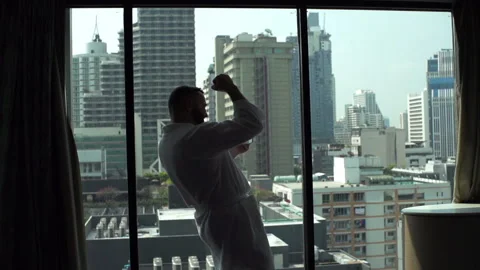 Man in bathrobe standing next to the window and receives good news on tablet Stock Footage 88167005