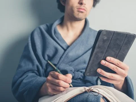 Man in bathrobe using tablet and taking notes Stock Photos