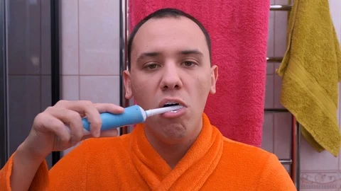 Man In Bathroom Brushing Teeth With Electric Toothbrush Video stock 122913409