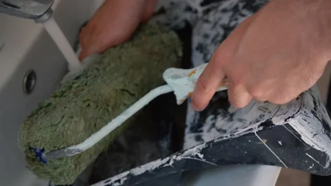 Man in the bathroom cleaning a paint roller. Stock Footage 155491383