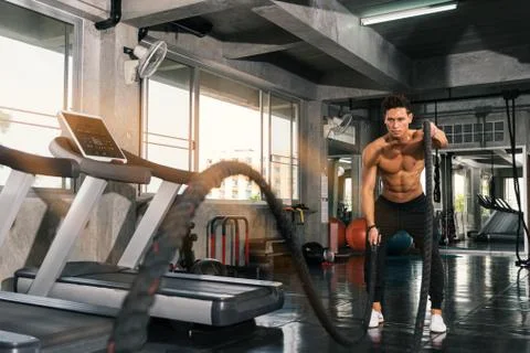 Man with battle rope doing exercise. Stock Photos