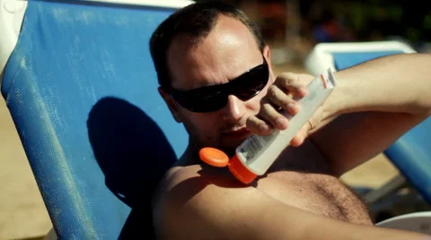 Man on the beach applying protection lotion Stock Footage 1068650