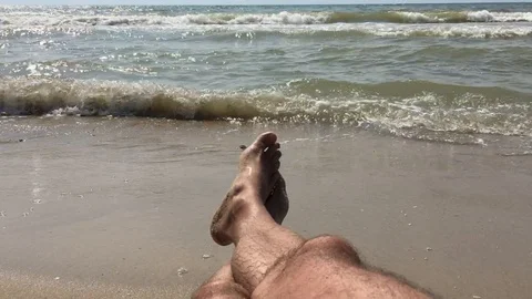 A man on the beach basking in the surf enjoys the sound of the ocean and roll Stock Footage 111576427