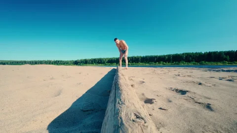 A man on the beach carries a log on his right shoulder. Stock Footage 313496839