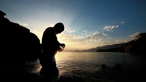 A man on the beach cleaning a fish in the sunset Stock Footage 81281867